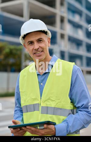 Construction engineer managing building project with digital tablet Stock Photo