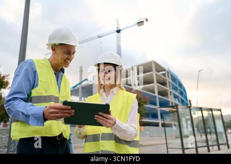 Construction engineers working on site discussing building plans Stock Photo