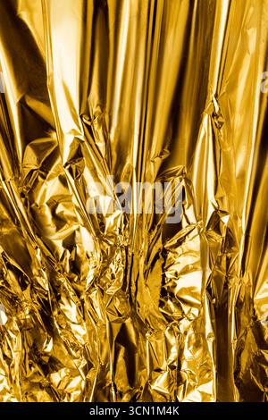 Golden crumpled metallic foil texture closeup as a background Stock Photo