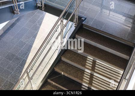 Modern staircase with metal railing. Interior design of office building. Empty steps with sunlight shadow. Architecture detail background. Stock Photo