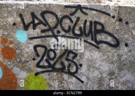 Graffiti on Weathered Concrete Wall With Spray Paint Tags, Colorful Dots, and Urban Texture. Bonifacio, Corsica, France Stock Photo