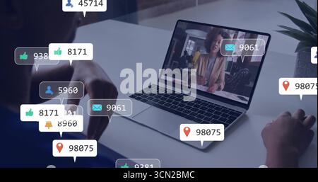 Collaborating colleagues pointing and typing on laptop at office desk, with plant and digital icons. Collaboration, teamwork, digital, modern, profess Stock Photo
