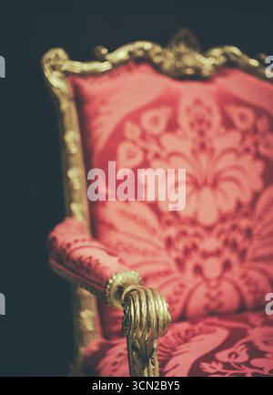 Close-Up Of A Luxurious Antique Armchair Or Throne With Golden Carved Details And Red Patterned Upholstery In Baroque Style Stock Photo