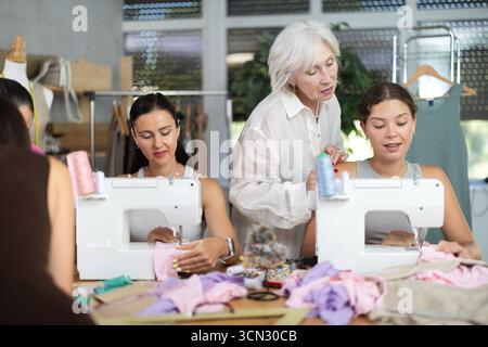 Sewing teacher guiding student during machine work Stock Photo