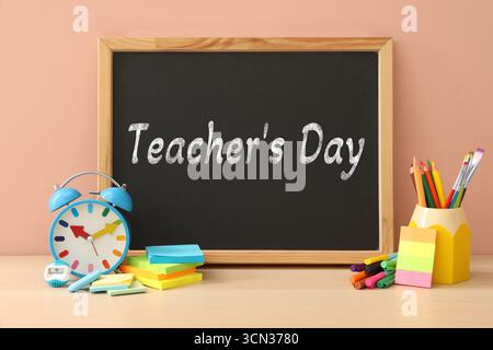 Happy Teacher's Day greeting card with stationery and text on small chalkboard Stock Photo