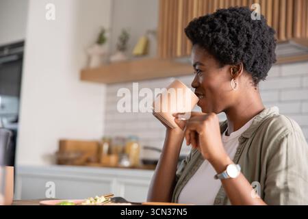 Ceramic mug sitting on dining table next to bowl of food in kitchen with subway tile backsplash Stock Photo