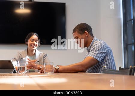 Diverse coworkers collaborating and using tablet with keyboard case at meeting room Stock Photo