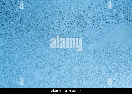 Water drops on glass in blue color temperature Stock Photo