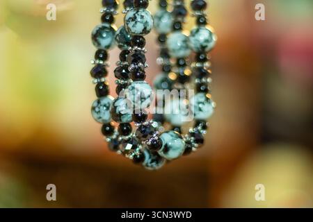 A close up, out of focus view of beaded seashell and plustic jewelry, bracelet or necklace. The beads are arranged in multiple strands, giving the ite Stock Photo