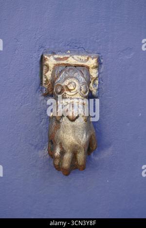 Rusty Ornate Door Knocker On Blue Wall With Weathered Finish and Decorative Details. Porto-Vecchio, Corsica, France Stock Photo