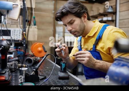 A skilled worker works on an electronic device Stock Photo