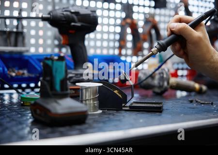 A man using a soldering iron on electronic equipment Stock Photo