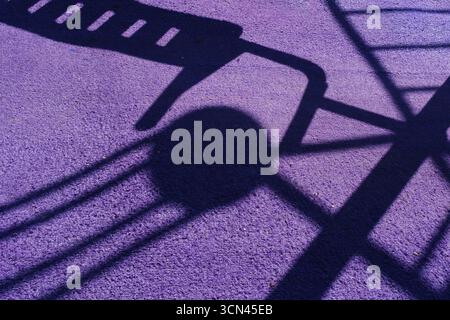 Playground shadows on purple ground creating abstract geometric pattern. Stock Photo