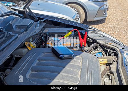 Jumpstart a dead car battery using a power bank in the parking lot Stock Photo
