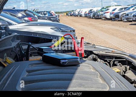 Jumpstart a dead car battery using a power bank in the parking lot Stock Photo