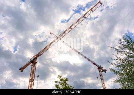 Berlin, Germany - August 20, 2025: Construction cranes towering against a backdrop of dramatic clouds, capturing urban development in Berlin, Germany. Stock Photo