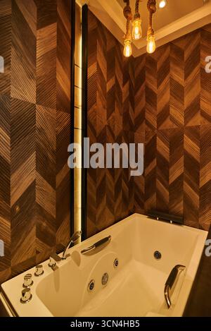 A luxurious bathroom featuring a jacuzzi tub and a unique wooden wall design. The space is designed for relaxation and comfort, creating a spa-like at Stock Photo