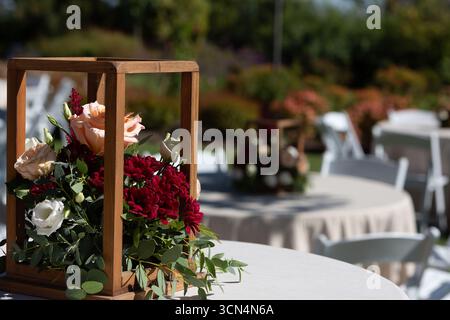 Wooden box centerpiece overflowing with fresh flowers decorating table at an outdoor wedding reception venue Stock Photo