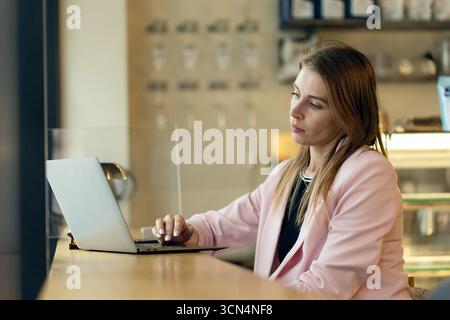 Young woman is working on a laptop at a cafe Stock Photo