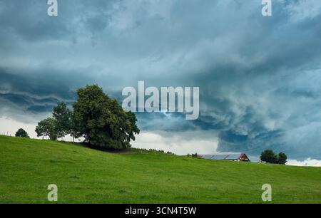 Dark storm clouds gathering over green hills Stock Photo