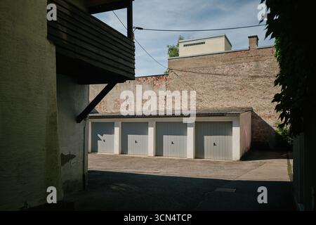 Four gray garage doors under a brick wall Stock Photo