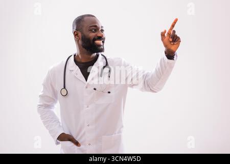 Portrait of African American male doctor who is having idea and pointing upside on the gray background. Stock Photo