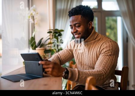 Freelancer using digital tablet to communicate online. He is sitting in bar and having online communication. Stock Photo