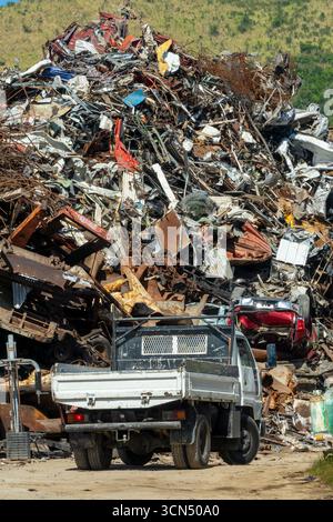 Truck in front of a large heap of scrap metal in a rubbish dump for recycling Stock Photo