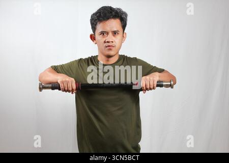 Asian man wearing green t-shirt doing weight training with light dumbbells Stock Photo