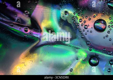 Abstract macro photo of liquid bubbles on a smooth surface with vivid colors of green, blue, purple, and pink blending together, creating shimmering r Stock Photo