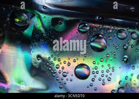 Abstract macro photo of liquid bubbles on a smooth surface with vivid colors of green, blue, purple, and pink blending together, creating shimmering r Stock Photo