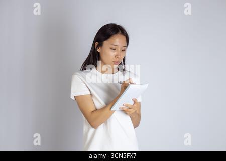 Woman in white shirt holding a tablet Stock Photo