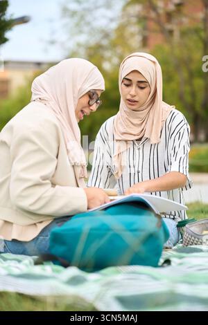 Muslim students studying together outdoors in park Stock Photo