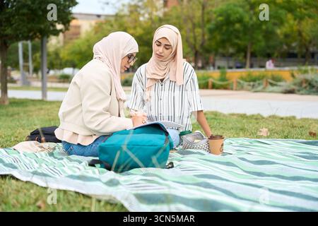 Muslim students studying together on green grass Stock Photo