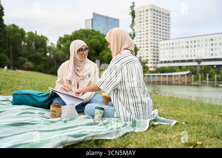 Muslim students studying together on picnic blanket Stock Photo