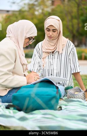 Muslim students studying outdoors, collaborating on education Stock Photo