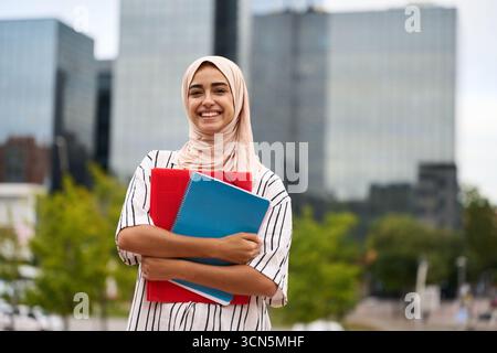 Muslim woman student holding books on campus Stock Photo