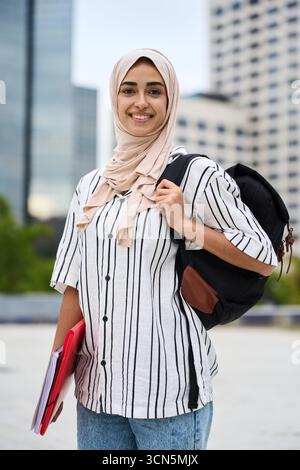 Muslim woman student smiling holding backpack and folders Stock Photo