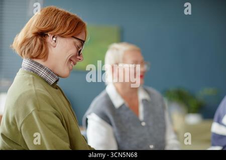 Young Caucasian Man Smiling While Listening during Group Meeting Indoors Stock Photo