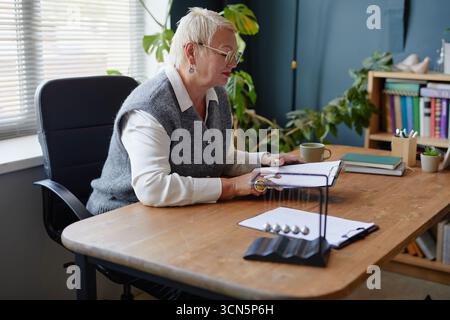 Middle Aged Caucasian Woman Reading Documents While Sitting at Office Desk Stock Photo