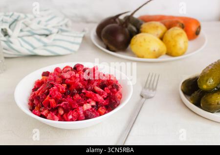 Salad vinaigrette in a white bowl with a fork with ingredients on a gray table. Concept of vegan and vegetarian cuisine. Horizontal orientation. Selec Stock Photo