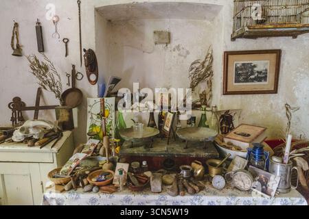 View of an eclectic assortment of antique tools, bottles, books, and trinkets arranged on a table against a weathered wall, Frattura Vecchia, Abruzzo, Italy. Stock Photo