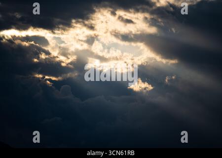 Sun light and rays breaking through thick storm clouds Stock Photo