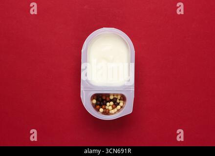 Quen in a plated box with chocolate corn balls on red background. Top view. Minimalism food concept. Stock Photo