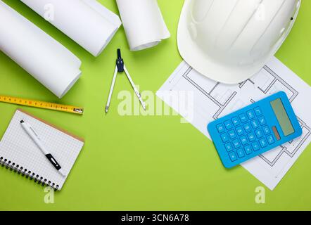 Engineering construction safety helmet, blueprint rolls, project plan and calculator on green background. Calculation of the cost building a house. To Stock Photo