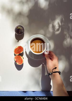 Coffee with Milk on White Saucer, Woman in Blue Summer Dress Touching Cup in Sunlight, Mediterranean Lifestyle Stock Photo