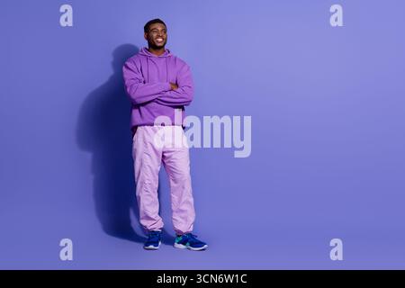 Young male model in vibrant casual purple outfit posing confidently against a violet background promoting fashionable leisure style Stock Photo