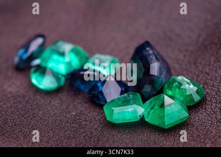 A pile of green and blue gemstones on a table. The stones are of different shapes and sizes, and they appear to be of high quality. Concept of luxury Stock Photo
