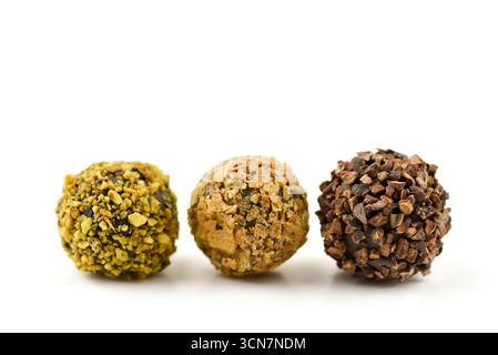 Three different colored chocolate covered balls are shown on a white background. The balls are of different sizes and colors, with one being green, on Stock Photo