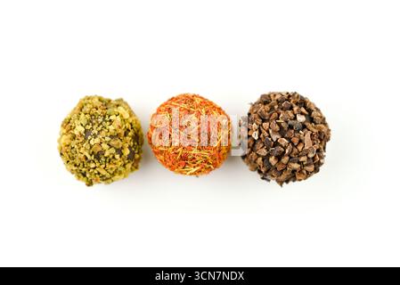 Three different colored balls with nuts and spices on top. The balls are arranged in a row. The top left ball is green, the middle one is orange, and Stock Photo